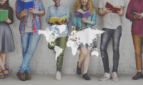 Bildung verbindet Sechs junge Erwachsene stehen nebeneinander vor einer weißen Backsteinwand und lesen Bücher in verschiedenen Farben. Ihre Gesichter sind größtenteils nicht sichtbar, der Fokus liegt auf den Büchern und ihrer Kleidung. Über das Bild ist eine transparente Weltkarte gelegt, die symbolisiert, dass Bildung Menschen weltweit verbindet.