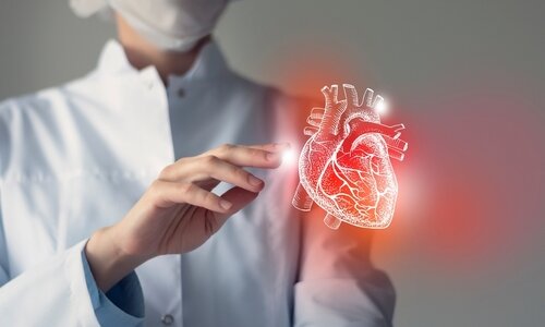 Ärztin mit Herz Ein Ärztin in weißer Kleidung und Schutzmaske berührt vorsichtig das Hologramm eines Herzes, das vor ihr schwebt.