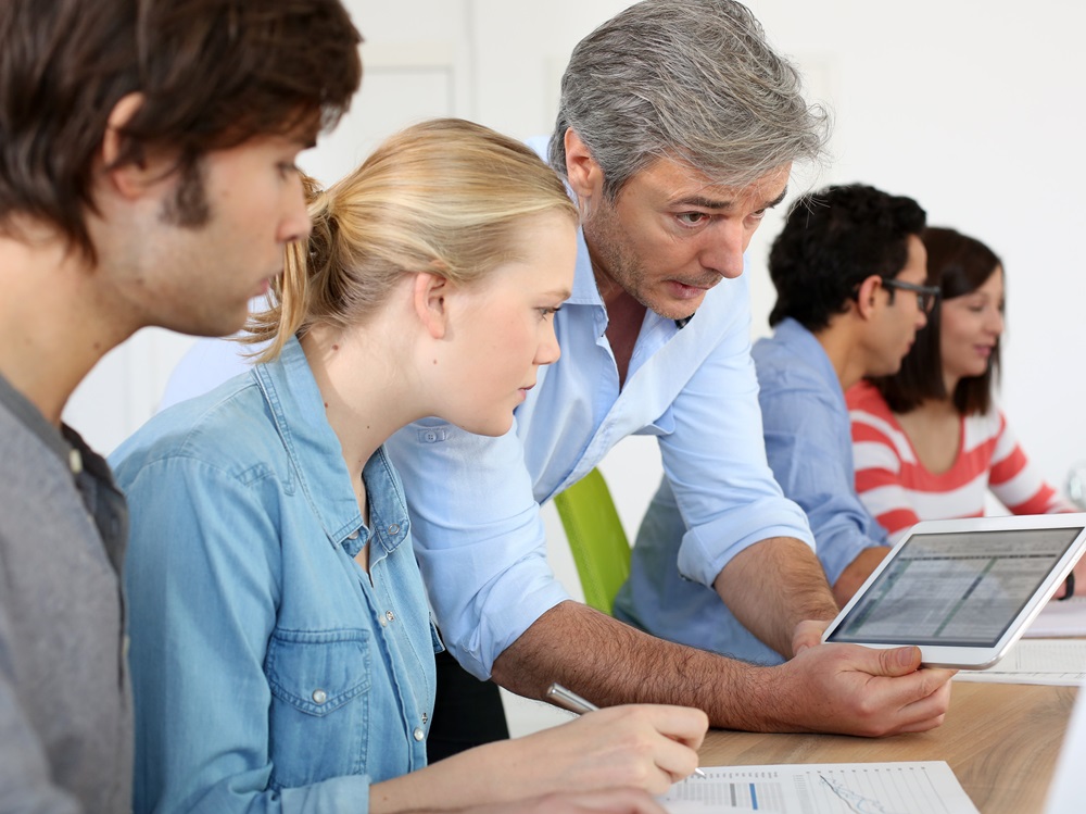 Gruppe bei einer Besprechung, eine Person hält ein Tablet